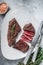 Roasted sliced rump beef meat steak on a plate with thyme. White background. Top view