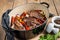 Roasted slow cooked lamb shanks with vegetables and herbs. Wooden background. Top view