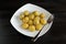 Roasted small potato tubers with spices on white plate