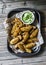 Roasted spices potato with avocado salsa on wooden background, top view. Delicious snack or appetizers.