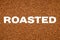 ROASTED text across instant coffee granules background