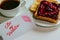 Roasted toast with blueberry jam and black coffe on the white table. Be My Valentine white message card with lips imprint