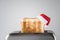 Roasted toast bread in a christmas Santa Claus red hat popping up of stainless steel retro toaster for breakfast preparation.
