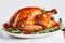 Roasted turkey on white dish garnished with fresh rosemary sprigs and red pepper corns. Traditional Christmas Thanksgiving holiday