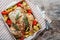 Roasted whole chicken stuffed with vegetables, tomatoes potato pepper and rosemary on vintage napkin wooden table background