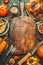Roasted whole chicken or turkey, pumpkins, corn and harvest vegetables with kitchen knife and cutlery served around aged wooden cu