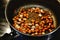 Roasting peanuts and jeera indian cumin on ghee on an electrical ceramic stovetop