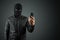 Robber, thug in a balaclava with a phone in his hands on a black background. Robbery, hacker, crime, theft. Copy space