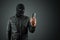 Robber, thug in a balaclava with a phone in his hands on a black background. Robbery, hacker, crime, theft. Copy space