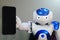 The robot holds the phone in his hand . A small robot with a human face and a humanoid body. Artificial intelligence-AI.