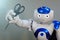 Robot holds scissors in his hand. Hairdresser. A small robot with a human face and a humanoid body. Artificial intelligence-AI.