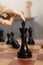 Robot moving chess piece on board, closeup. Wooden hand representing artificial intelligence