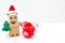 A robot in a santa hat holds a Christmas tree and christmas toy. Copy space