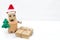 A robot in a santa hat holds a Christmas tree and gift box. Copy