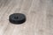 Robot vacuum cleaner black on the floor is cleaning, gray laminate