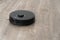 Robot vacuum cleaner black on the floor is cleaning, gray laminate