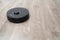 Robot vacuum cleaner black on the floor is cleaning, gray laminate