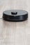 Robot vacuum cleaner black on the floor is cleaning, gray laminate