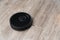 Robot vacuum cleaner black on the floor is cleaning, gray laminate