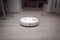 Robot vacuum cleaner cleans the apartment. white robot vacuum cleaner in interior