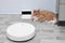 A robot vacuum cleaner goes to  charging station and a ginger cat lying on the floor
