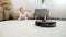 Robot vacuum cleaner moving toward little baby boy crawling on floor at house. Concept of hygiene, household gadgets and