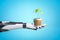 Robotic hand holding flower pot with new green sprout on blue background
