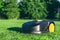 Robotic Lawn Mower cutting grass in the garden. Automatic robot lawnmower in modern garden on sunny day