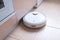 Robotic vacuum cleaner on the floor cleaning the kitchen. Smart cleaning technology.