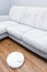 Robotic vacuum cleaner on laminate floor near sofa closeup, smart home robotics wireless cleaning for simplify routine housework,