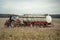 Robust red tractor pulling a pristine white tanker trailer along a flat, rural landscape