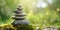 Rock balancing banner. Stones piled in balanced stacks in front of blurry green garden or forest background with copy space