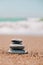 Rock balancing on ocean beach. Pyramid of pebbles on sandy shore. Stable pile or heap in soft focus with bokeh, close up