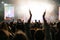 Rock Band Performing at a Concert in a NightClub. Front Row Crowd is Partying. Silhouettes of Fans Clap Hands in Front of Bright