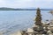 Rock cairn the art of stone balancing on a stone near a blue water flowing lake.