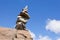 Rock cairn trail marker on boulder with blue sky