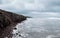 A rock cliff above the water with a tidal shoreline. Tersky coast of the White Sea.. Panoramic view