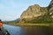 Rock cliff and green forest on limestone mountain on the vast wetland