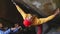 A rock climber climbs a boulder in the open air.