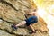 Rock climber climbs bouldering on a cliff on forest. Low angle of strong rock climbing man hanging free on rock with