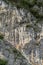 Rock climber dressed in bright yellow climbing a steep vertical difficult climbing route in the Italian Alps of Lombardy