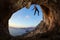 Rock climber gripping handhold on ceiling in cave