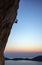 Rock climber on overhanging cliff at sunset.