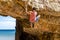 A rock climber safely climbing a yellow cliff in Algarve, Portugal