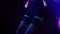 Rock female singer in black mini dress, stockings perform on stage of nightclub. Blue spotlights