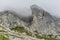 Rock formation covered in fog in the middle of mountainous scenery in Dolomites, Italy