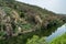 Rock formation known as Mondego bookshop on the riverbank hill with trees reflected in the water, Penacova PORTUGAL