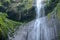 Rock gap in the middle of the Madakaripura waterfall. Water falls on a rock of black stone covered with moss.