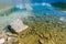 A rock in a lake with transparent blue water in the french alps