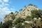 Rock in the mountains with poor vegetation before blue sky with white clouds on bright sunny day